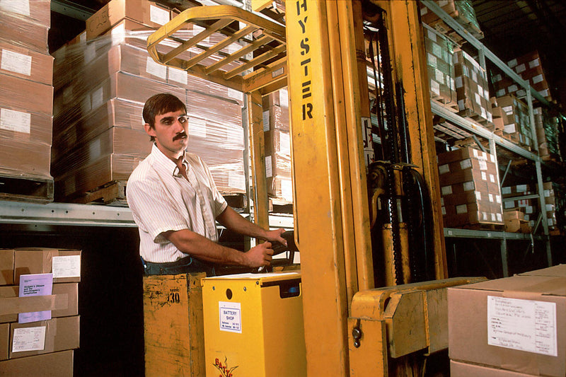 A man driving a fork lift in the warehouse