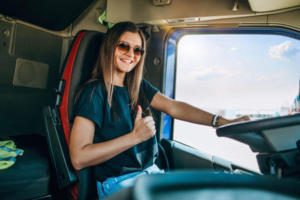 beautiful young woman professional truck driver sitting and driving big truck.