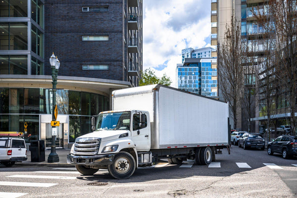 Big rig white semi truck with long box trailer making local commercial delivery