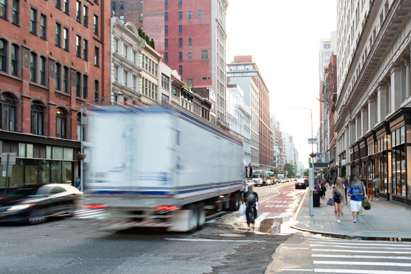 delivery truck speeding past the people walk down the sidewalk