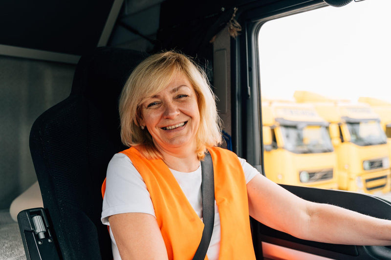 Mature woman truck driver steering wheel inside lorry cabin