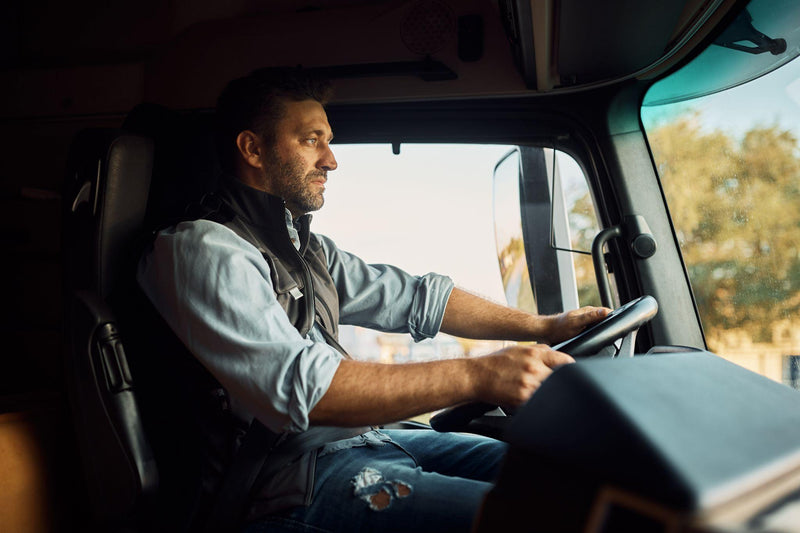 Mid adult truck driver driving his truck on the road.