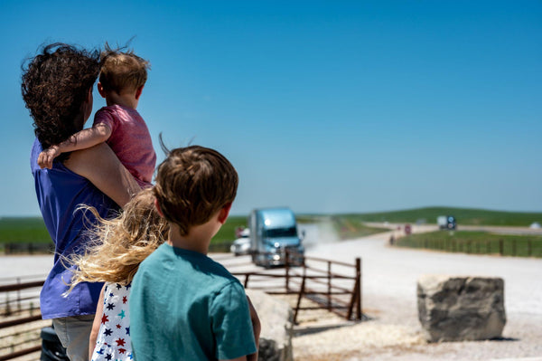 Mother and children looking into the distance while a semi truck comes up the road