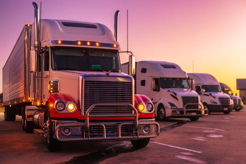 Parked American semi trucks at the rest area, on a vibrant sunset evening