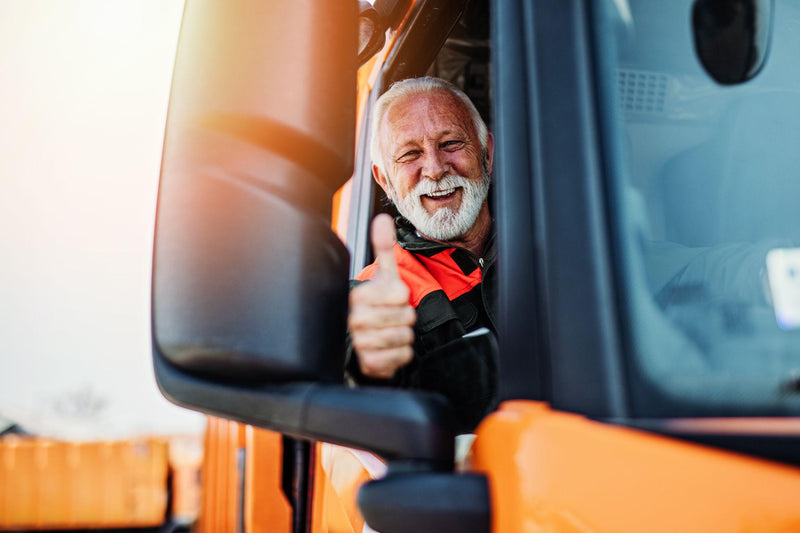 Senior garbage removal worker driving a waste truck.