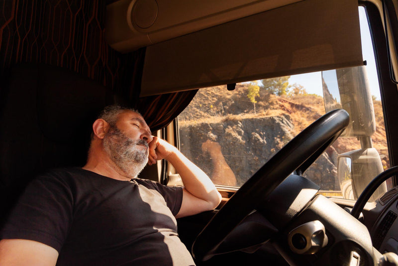 Truck driver resting in the seat of the truck while waiting to load.