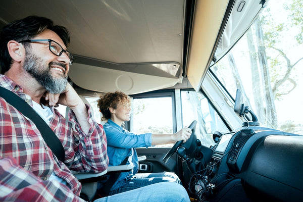 Woman driver driving a camper van with happy man on passenger seat.